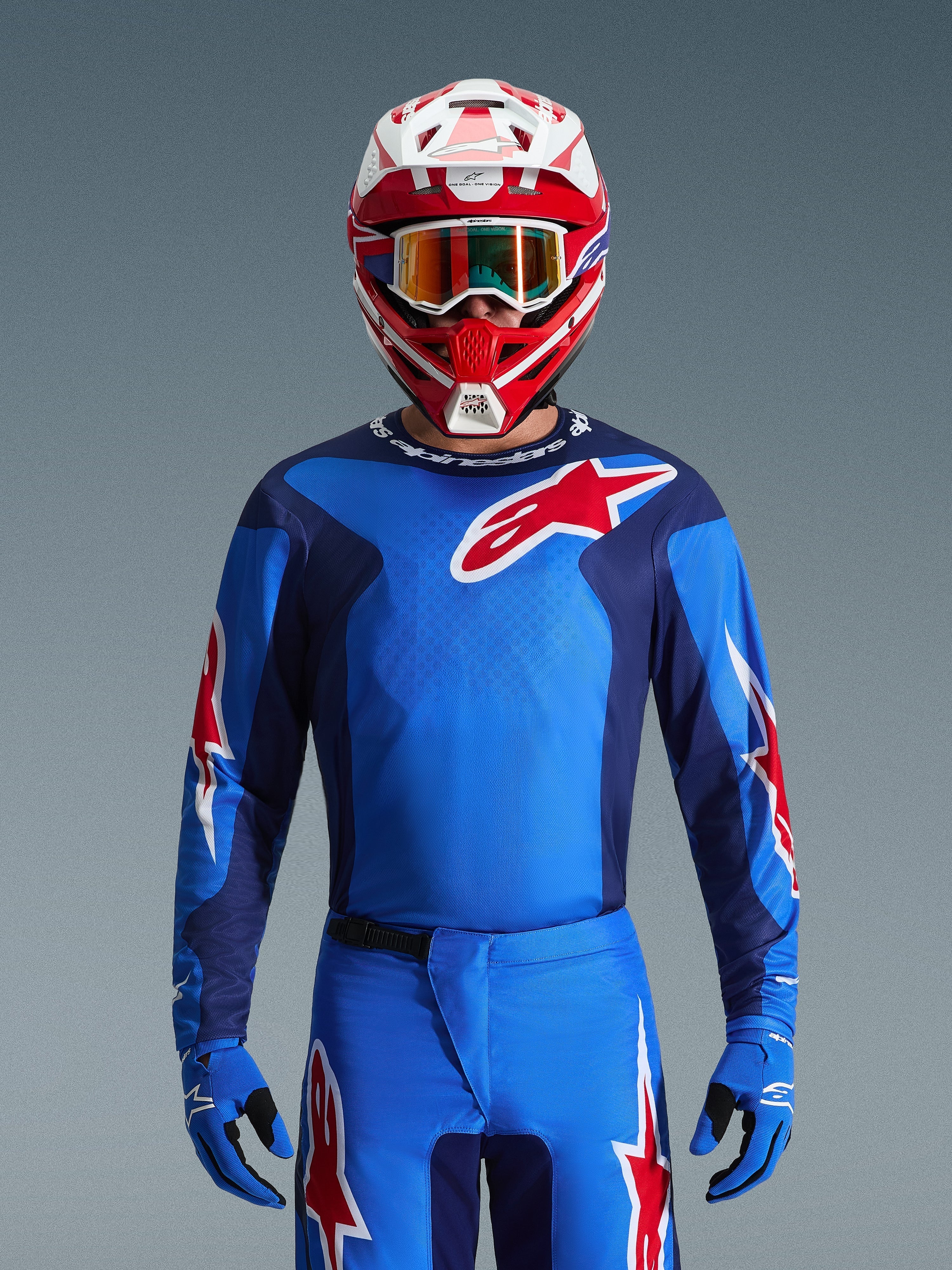 Alpinestars 2026 Fluid Grid Jersey, Blue and Red motocross jersey, worn with matching pants and a red and white helmet, featuring prominent red star logos and an athletic fit designed for off-road racing performance