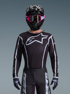 Alpinestars 2026 Fluid Apex Gear Set, Motocross jersey and pants in black and white, features large chest logo and geometric line designs, worn with a black helmet and pink goggles, performance gear for off-road motocross racing.