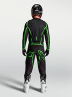 Alpinestars Fluid Apex V2 Jersey, motocross performance gear, black and green fluo, rear view on rider with white boots.
