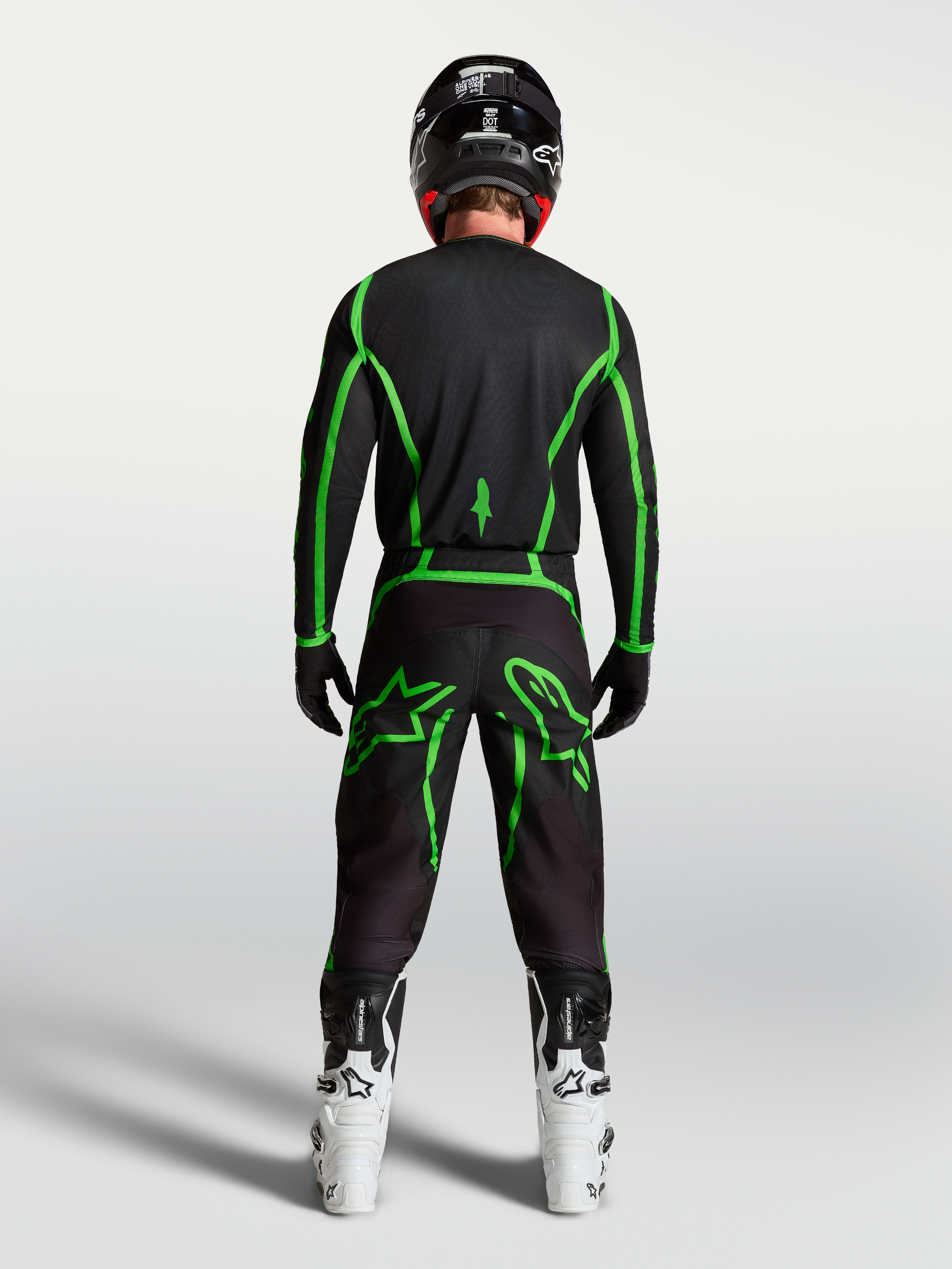 Alpinestars Fluid Apex V2 Jersey, motocross performance gear, black and green fluo, rear view on rider with white boots.