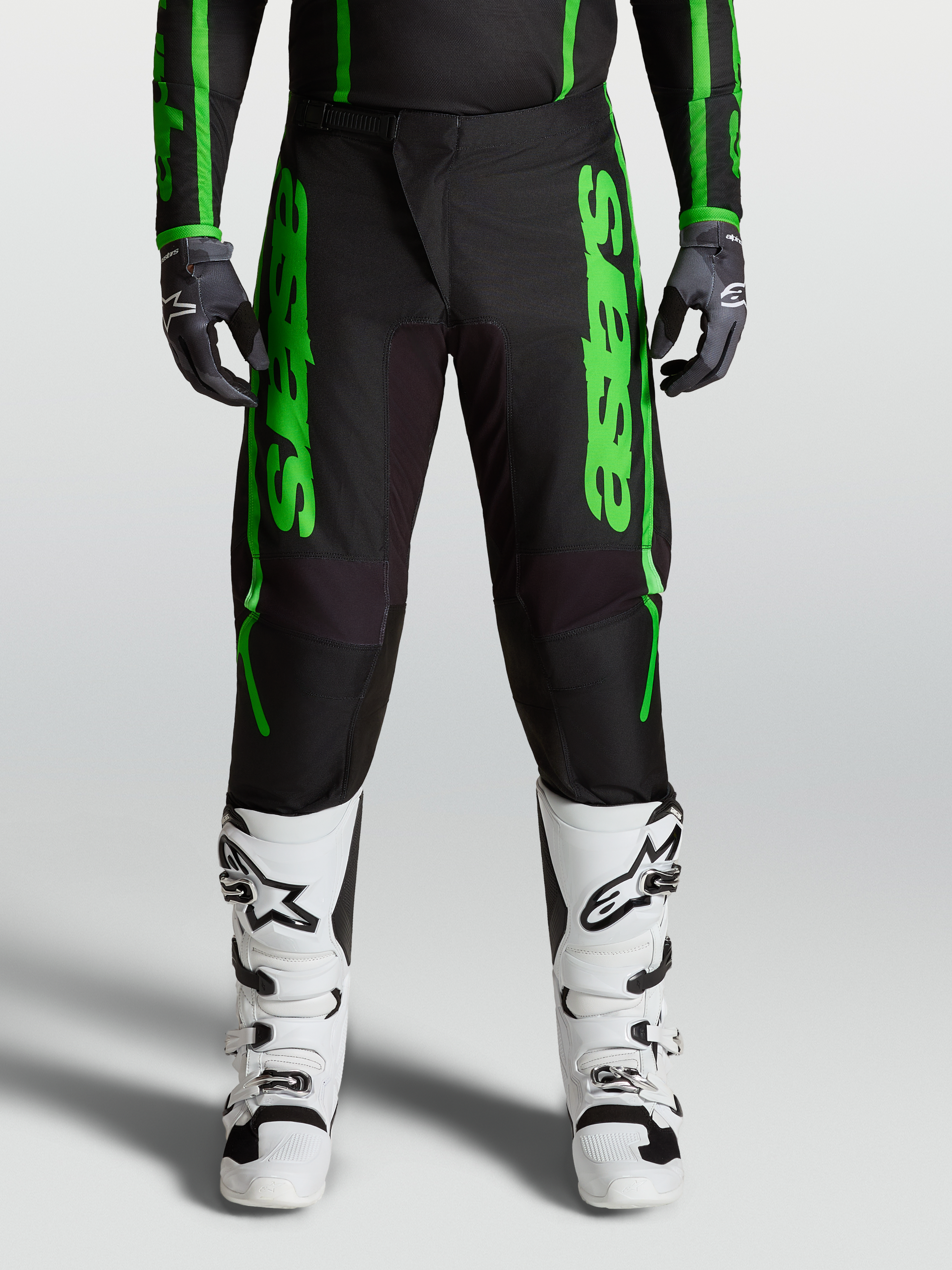 Alpinestars Fluid Apex V2 Pants, green and black motocross performance pants with reinforced knees and matching white boots.