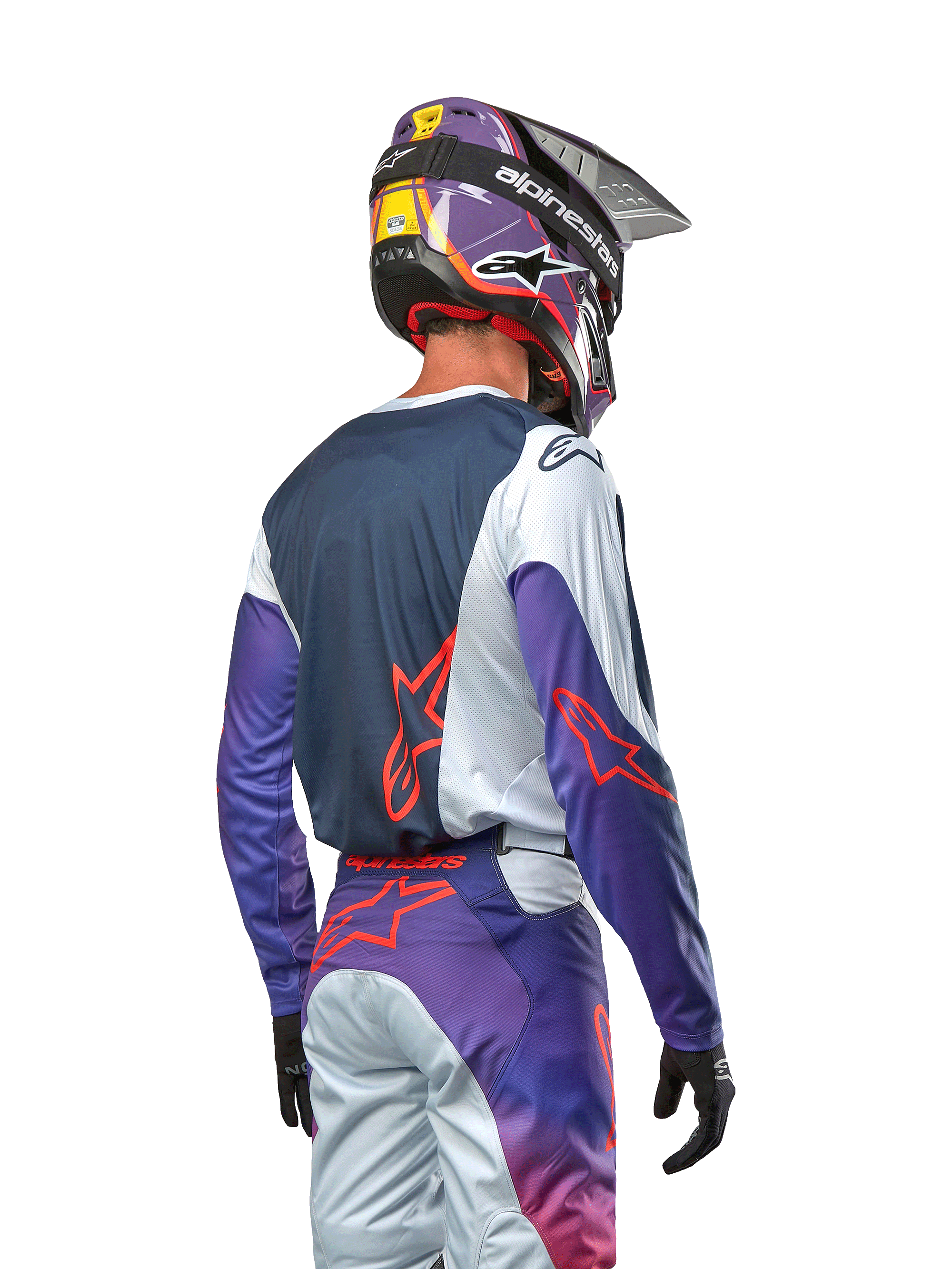 Motocross rider viewed from the back wearing the 2024 Racer Hoen Jersey, navy blue back panel with light gray shoulders and purple sleeves, hot orange Alpinestars logos, matching purple and gray pants with a purple motocross helmet, complete off-road racing kit