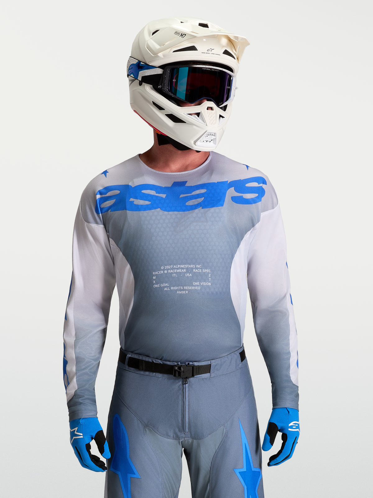 Alpinestars Racer Amber Jersey, Men's Motocross Gear in Gray and UCLA Blue, paired with a white MX helmet and goggles.