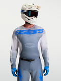 Alpinestars Racer Amber Jersey, Men's Motocross Gear in Gray and UCLA Blue, paired with a white MX helmet and goggles.