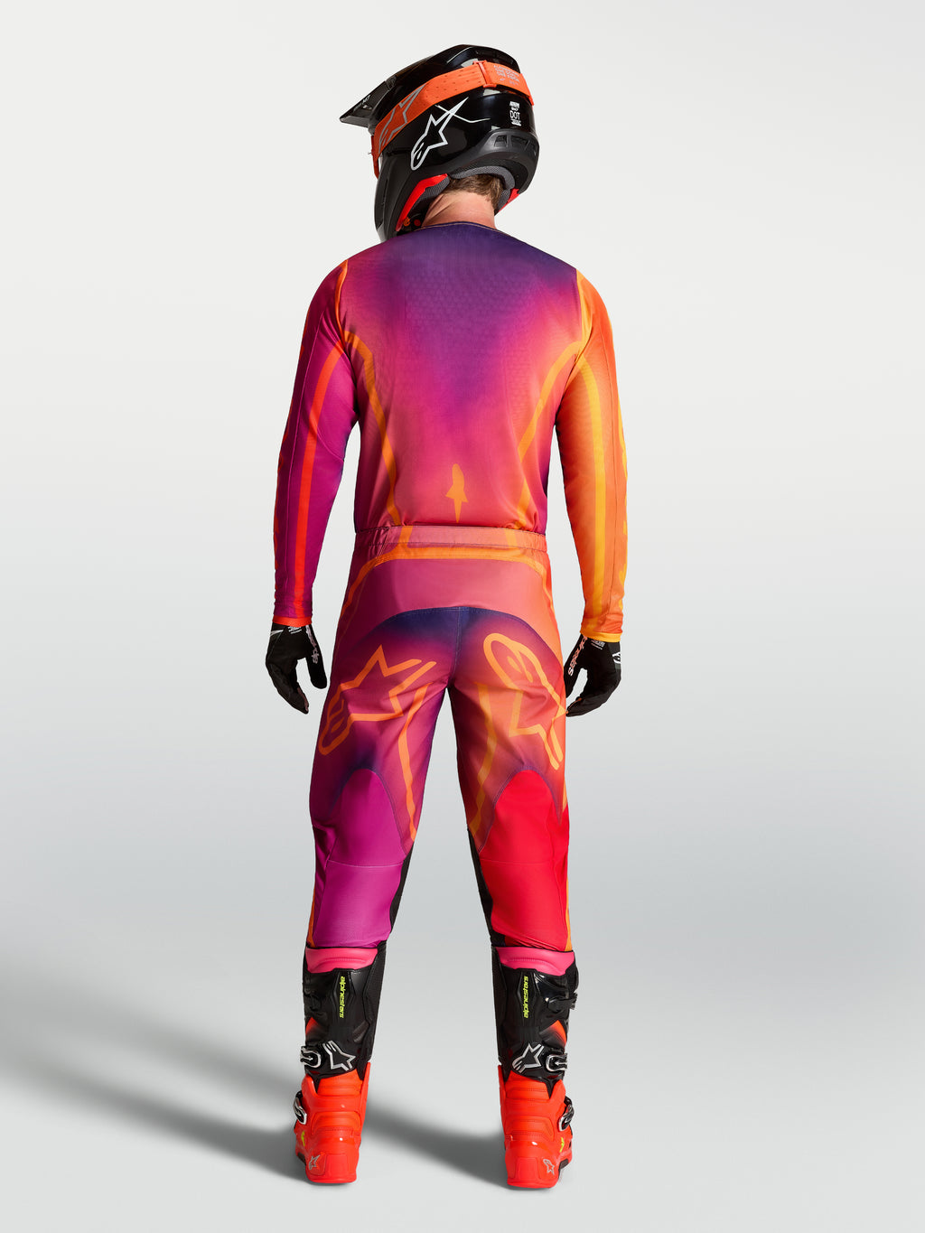 Alpinestars Fluid Kepler Jersey, men's purple and orange motocross gear on a rider with matching MX pants, seen from behind.