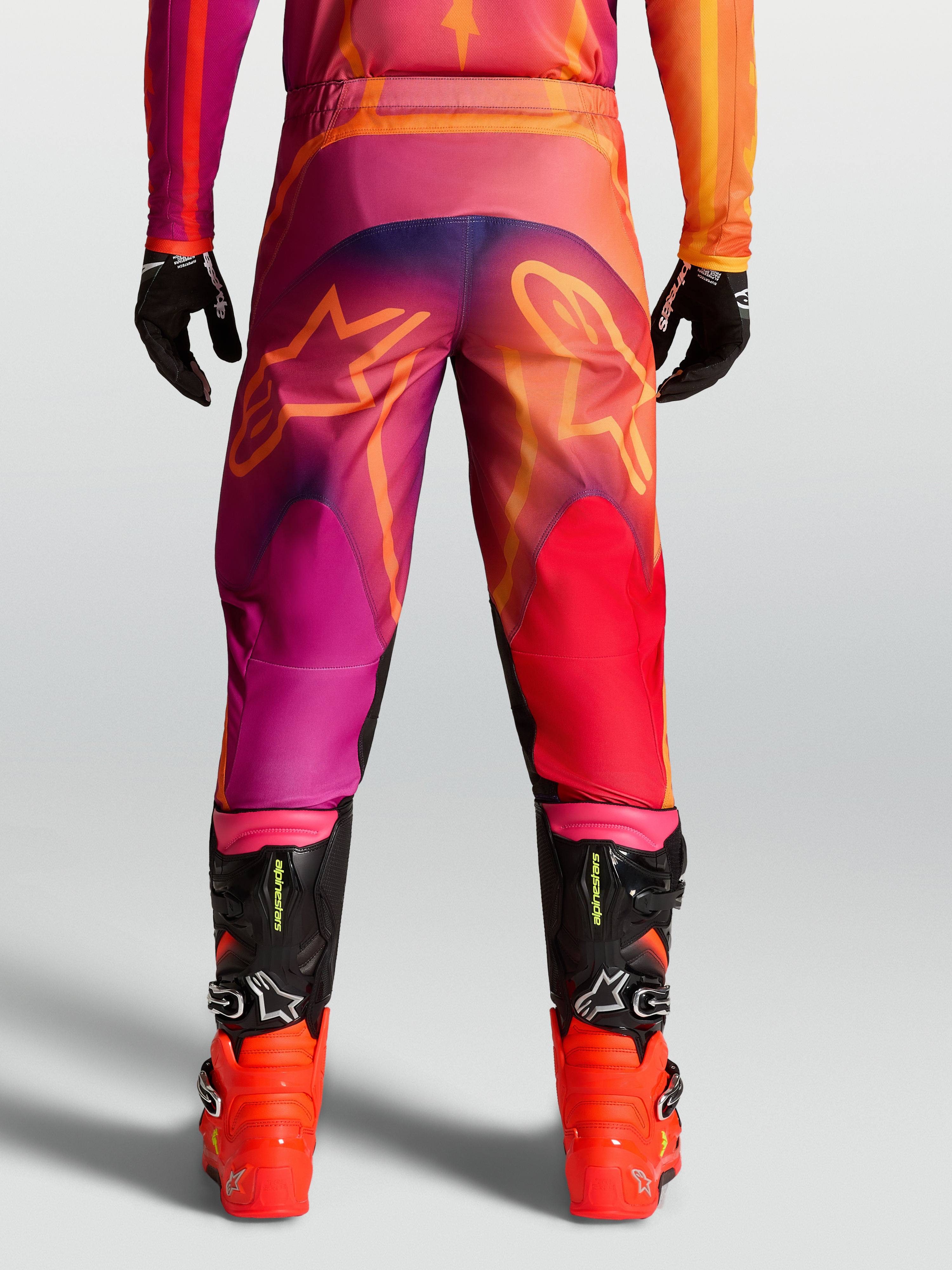 Alpinestars Fluid Kepler Pants, Men's Motocross Pants in Purple and Orange with rear star graphics and black racing boots.