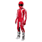 Motocross rider wearing complete racing gear, Alpinestars 2024 Fluid Lurv Jersey in Mars Red and White, matching red pants with white accents, red helmet, red gloves, and white and black boots, coordinated outfit for off-road racing