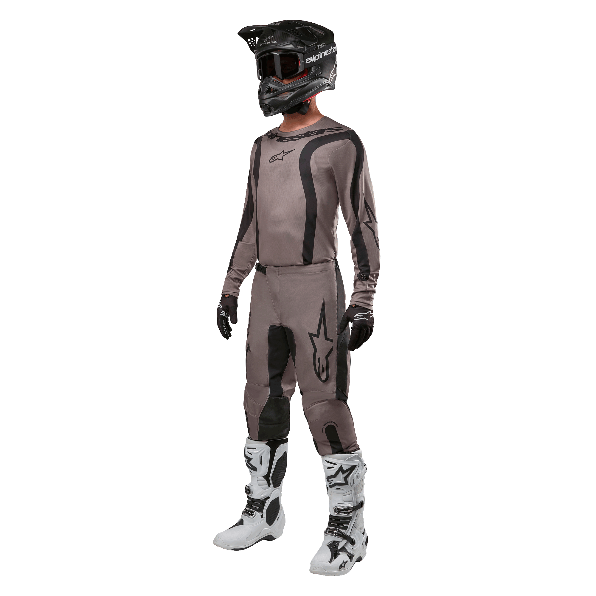 Motocross rider wearing complete racing gear featuring the Alpinestars 2024 Fluid Lurv Jersey in Mud Black, paired with matching pants, black helmet with goggles, white and black boots, and black gloves, coordinated outfit for off-road racing