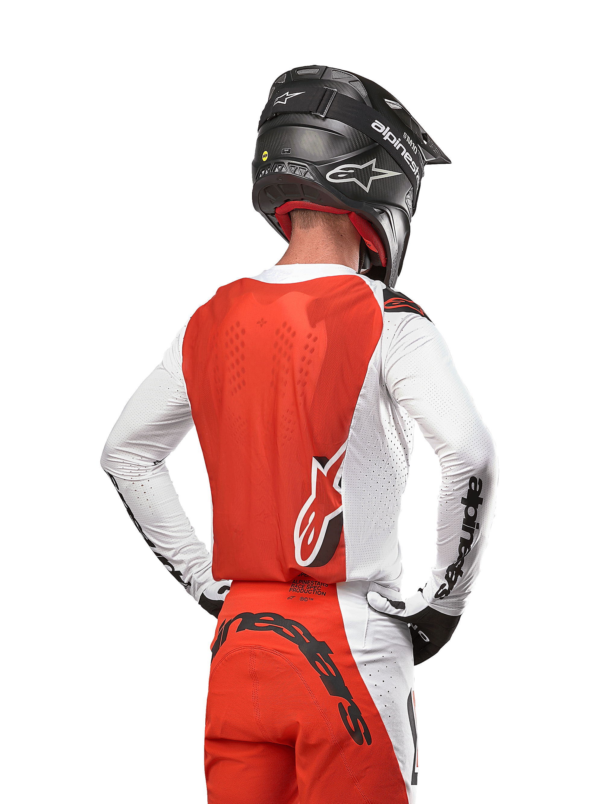 Motocross rider wearing the 2024 Supertech Ward Jersey in White Hot Orange, rear view showing orange back panel and white sleeves with black Alpinestars branding, paired with matching pants and a black helmet, coordinated professional gear for off-road racing