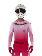 Motocross rider wearing Alpinestars 2024 Supertech Dade Jersey in Red Berry Lilac, matching pants, white helmet with black goggles, and red gloves, coordinated professional racing outfit with gradient pink and red tones