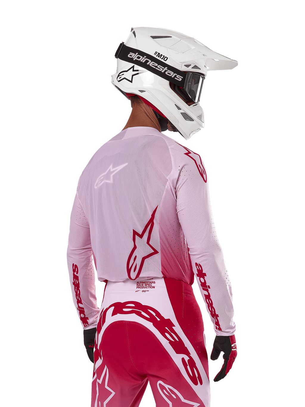 Motocross rider viewed from the back wearing the Alpinestars 2024 Supertech Dade Jersey in Red Berry Lilac, featuring breathable mesh panels and red Alpinestars logos, paired with matching red and lilac pants and a white Alpinestars helmet with goggles, professional off-road racing gear