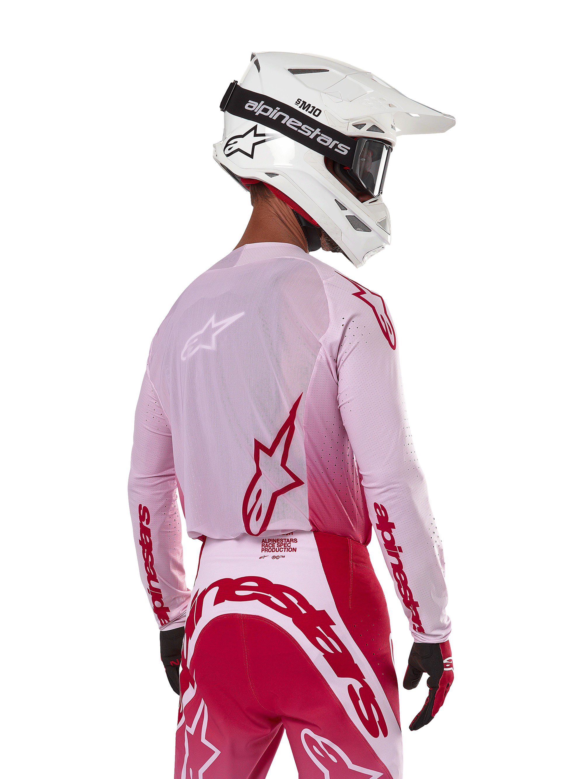 Motocross rider viewed from the back wearing the Alpinestars 2024 Supertech Dade Jersey in Red Berry Lilac, featuring breathable mesh panels and red Alpinestars logos, paired with matching red and lilac pants and a white Alpinestars helmet with goggles, professional off-road racing gear