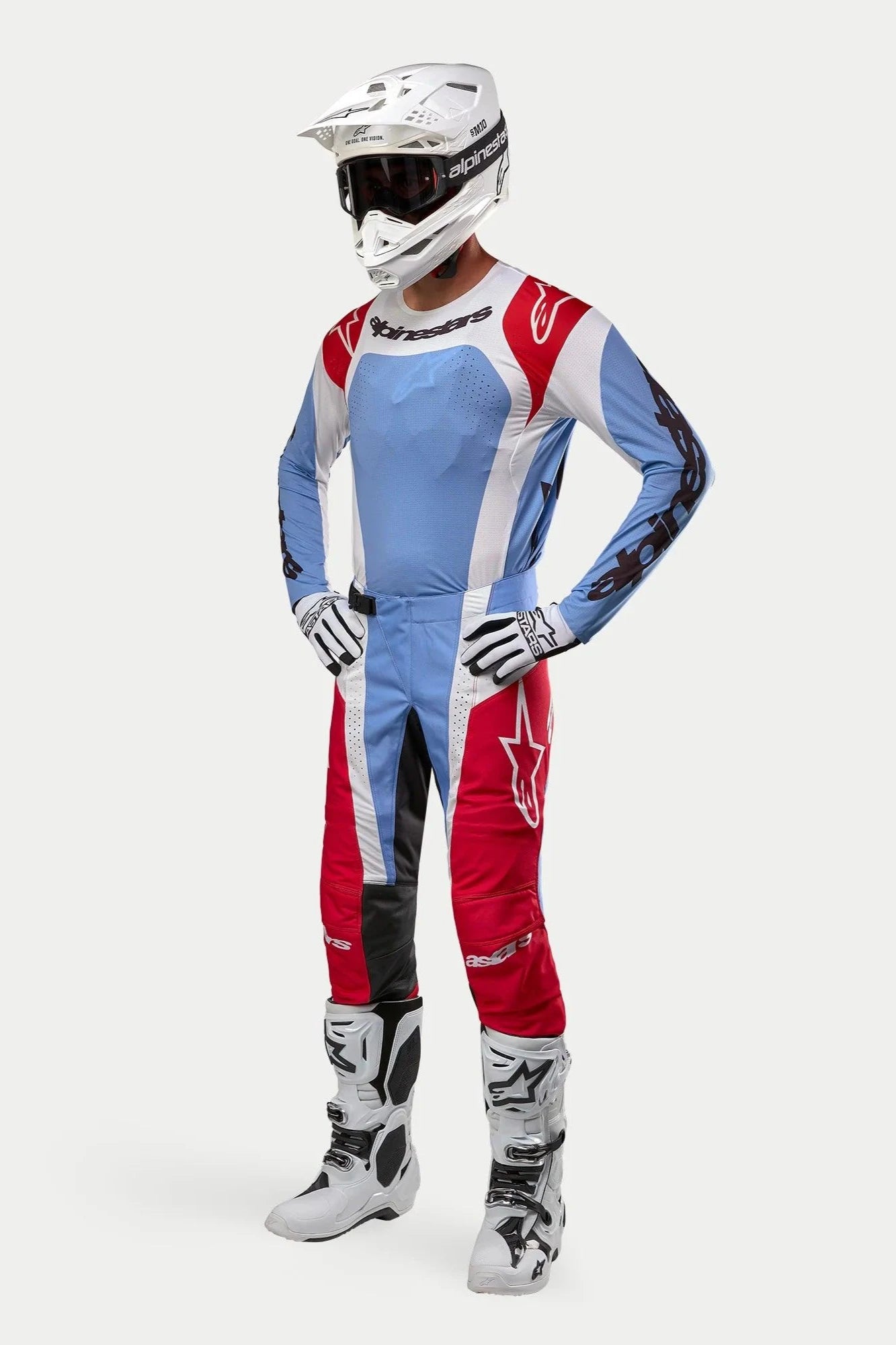 Motocross rider wearing Alpinestars 2024 Techstar Ocuri gear, Light Blue Mars Red and White jersey and pants, white helmet with goggles, white and black gloves and boots, professional racing outfit for off-road performance