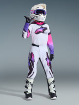 Young motocross rider wearing complete racing gear, 2026 Youth Supertech Vista Jersey in White Purple Black with pink accents, matching motocross pants, white helmet with purple goggles, and white and black boots, coordinated pro-level youth off-road outfit