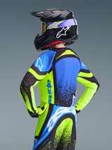 Youth motocross rider from behind wearing the Alpinestars 2026 Youth Supertech Nomur Jersey, Dark Navy and Yellow Fluo with Blue accents, coordinated with matching black helmet and pants, professional off-road racing gear.