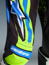 Alpinestars 2026 Youth Supertech Nomur Motocross Gear, close-up of pants in Dark Navy and Yellow Fluo with UCLA Blue accents, featuring the astars logo and laser-cut ventilation perforations, technical racing apparel