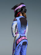 Rear view of a motocross rider wearing the Alpinestars 2026 Stella Techstar Nomur Gear Set, Light Blue with Pink and Black accents, matching jersey and pants, black helmet with pink goggles, ergonomic women's fit for off-road racing.