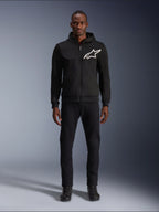 Alpinestars Chrome V2 Sport Hoodie, Black and White motorcycle hoodie, featuring a large white Alpinestars logo on the chest, zip-up front and hood, worn by a model standing with black pants and boots, urban-style protective riding gear.