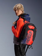 Alpinestars MM93 City Hunter V2 Backpack, black with red fluo and navy blue accents, featuring Marc Marquez MM93 signature graphics, worn with a coordinating sport hoodie, sleek aerodynamic profile for motorcycle commuting