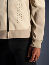 Alpinestars Radium Tech Hoodie in Mastic Aluminum, close-up view of chest and sleeve, vertical black text branding 'Alpinestars One Goal One Vision', ribbed stretch cuff and zipper detail, urban motorcycle textile jacket.