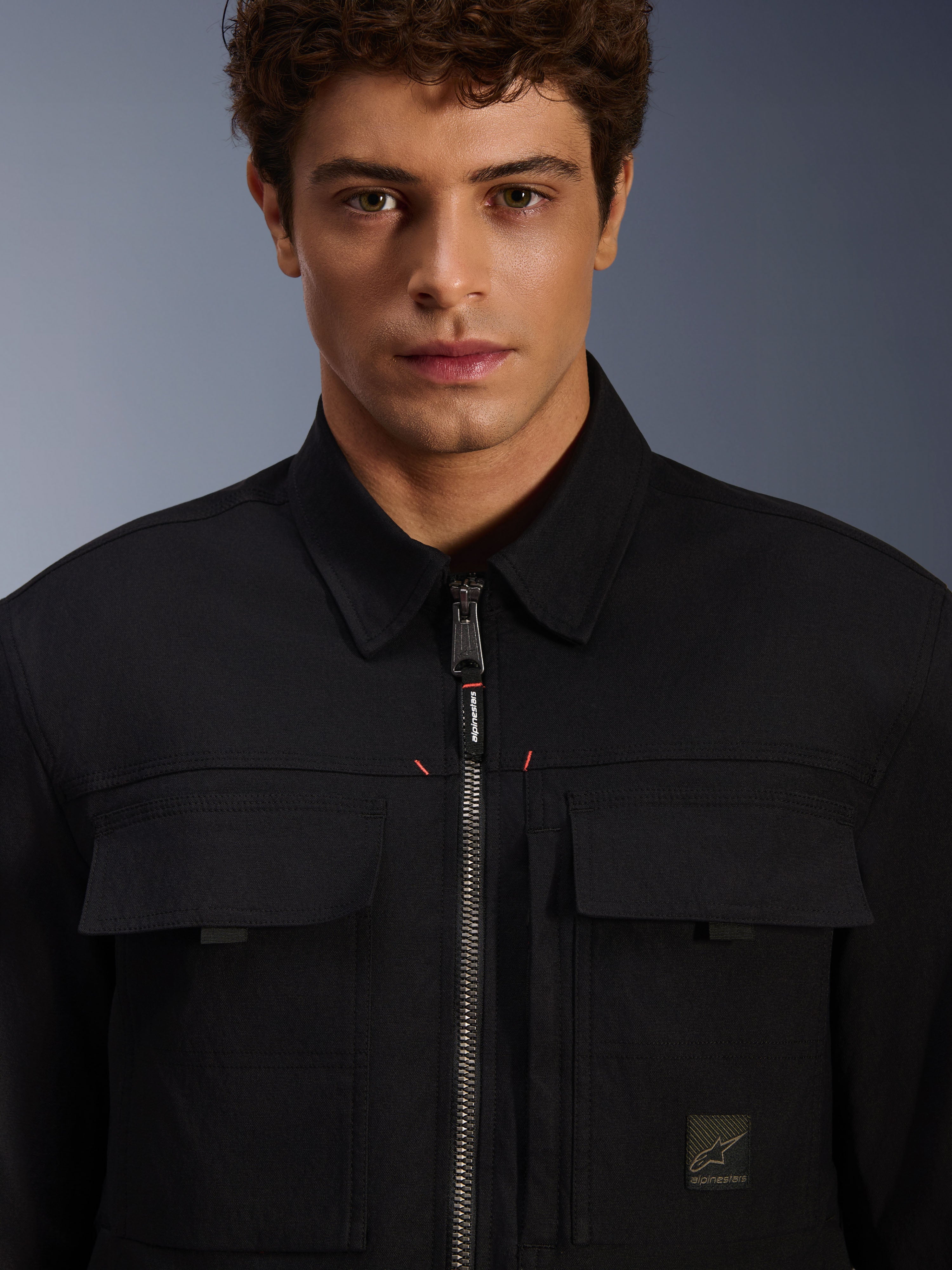Alpinestars Bryon Water Resistant Overshirt, Black, close-up view of front zipper and chest pockets, durable waxed canvas texture, minimalist urban design with branded accents and woven logo label