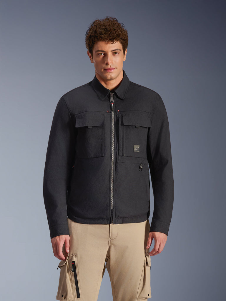 Alpinestars Bryon Water Resistant Overshirt, Black, urban motorcycle jacket with workwear-inspired styling, featuring two large chest cargo pockets and a full-length zipper, made from waxed canvas, worn by a model with beige cargo pants for a contemporary utility look.