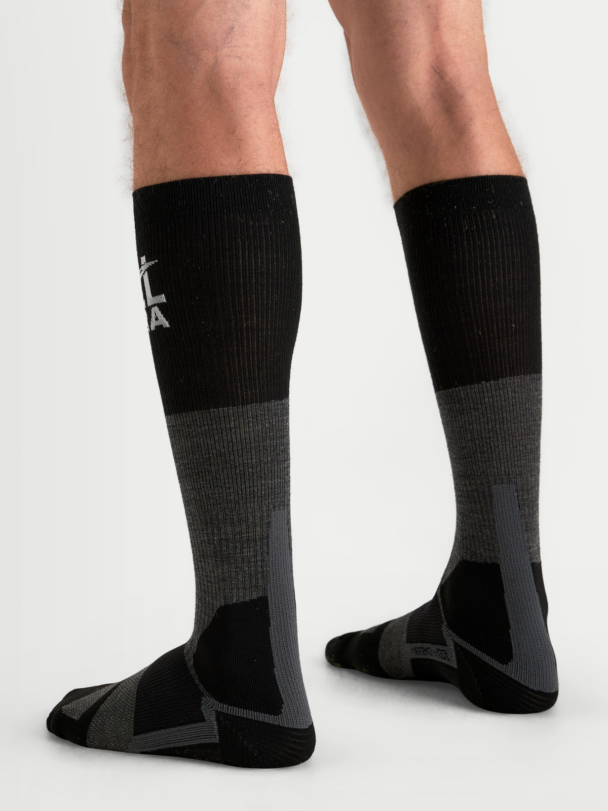 Alpinestars AT-8 Merino Socks, adventure motorcycle socks worn on a model, tar gray and black, over-the-calf thermal performance gear with reinforced cushioning