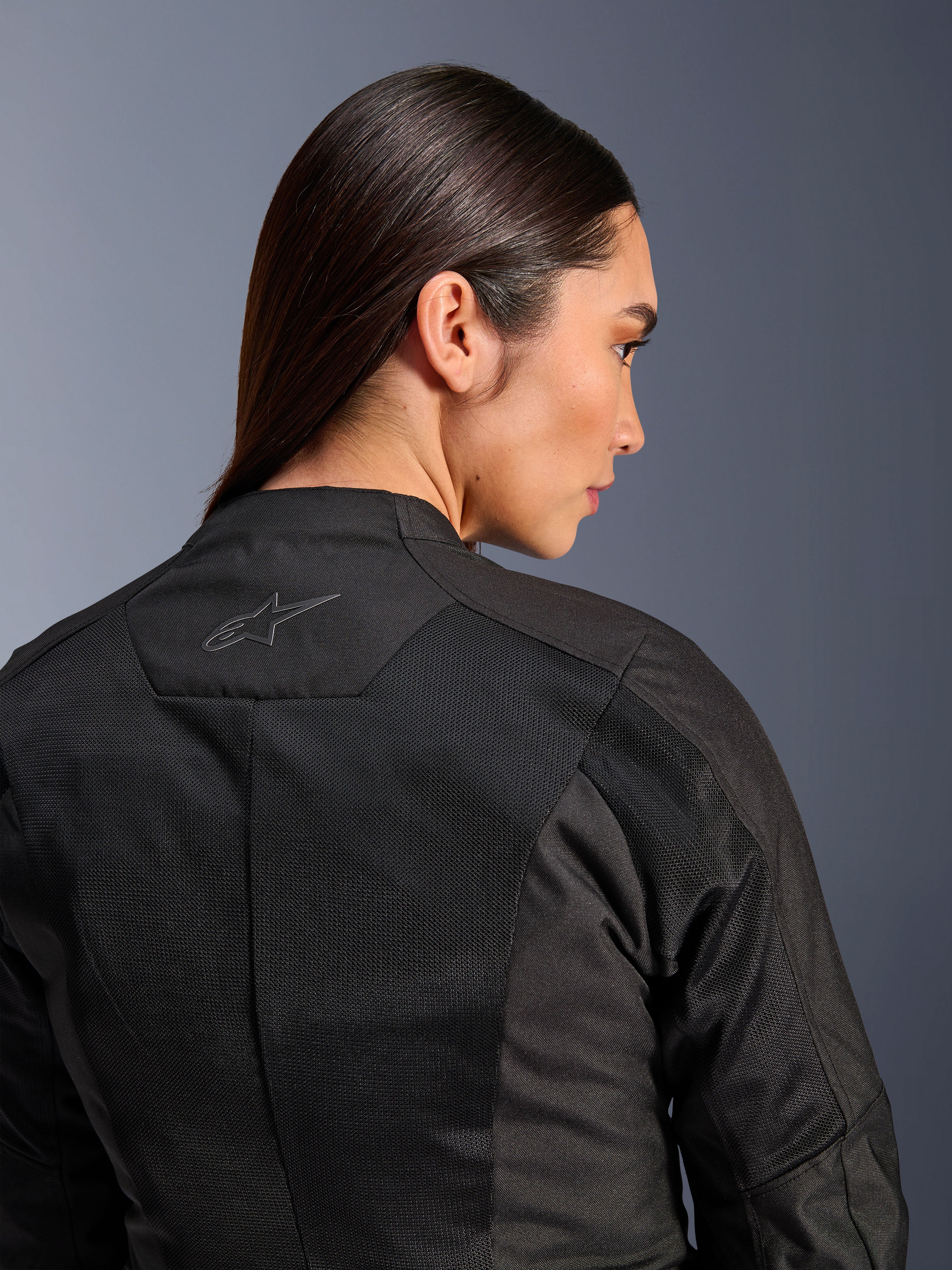 Alpinestars Woman Stella C-1 Air Jacket, Textile Motorcycle Jacket, Black, close-up rear view showing tech mesh ventilation panels and a reflective star logo on the upper back, modern urban riding gear