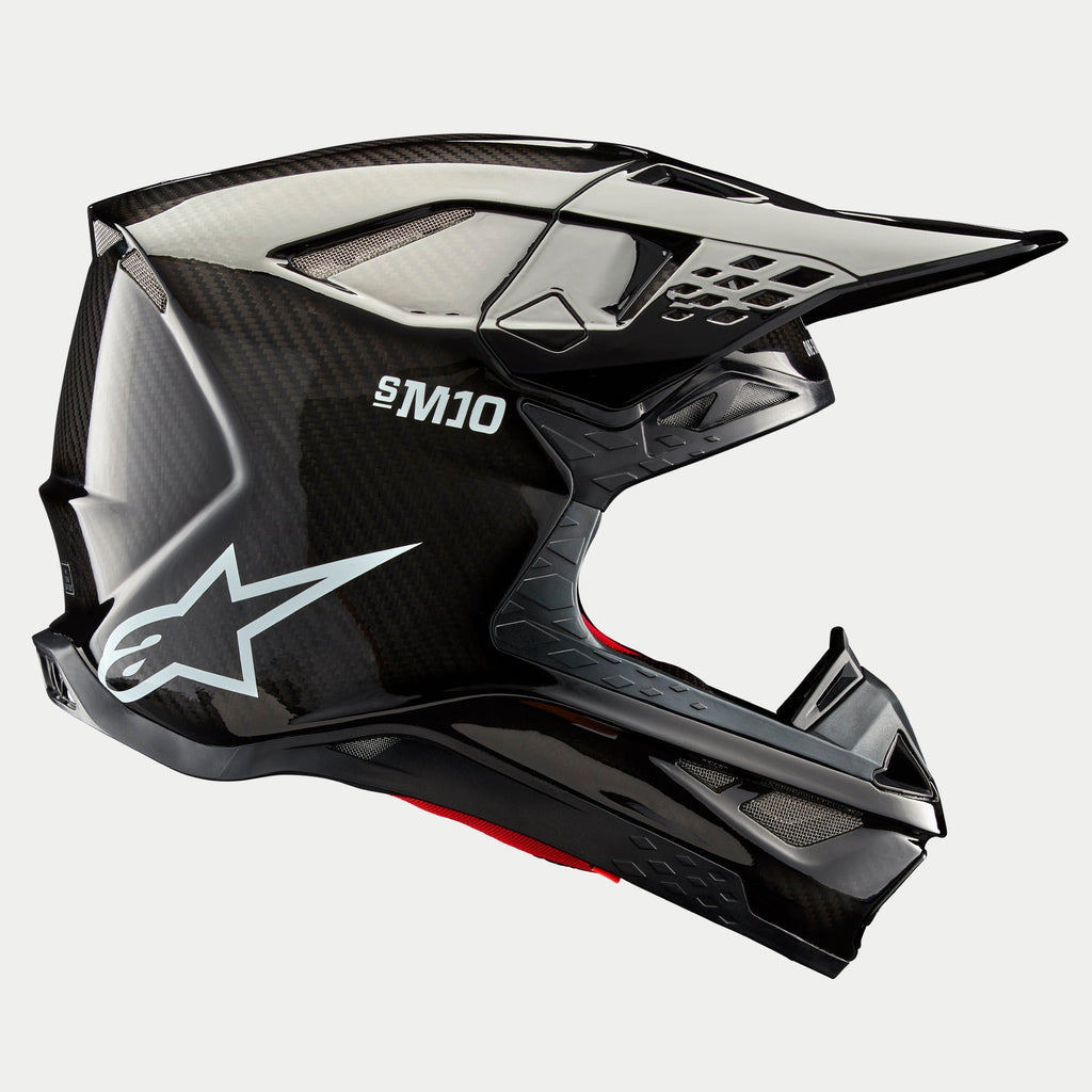 Alpinestars Supertech M10 Solid Helmet, Black Glossy Carbon, Motocross Helmet, side profile view showing glossy carbon fiber weave, S-M10 branding, white Alpinestars star logo, aerodynamic design with peak visor and ventilation ports
