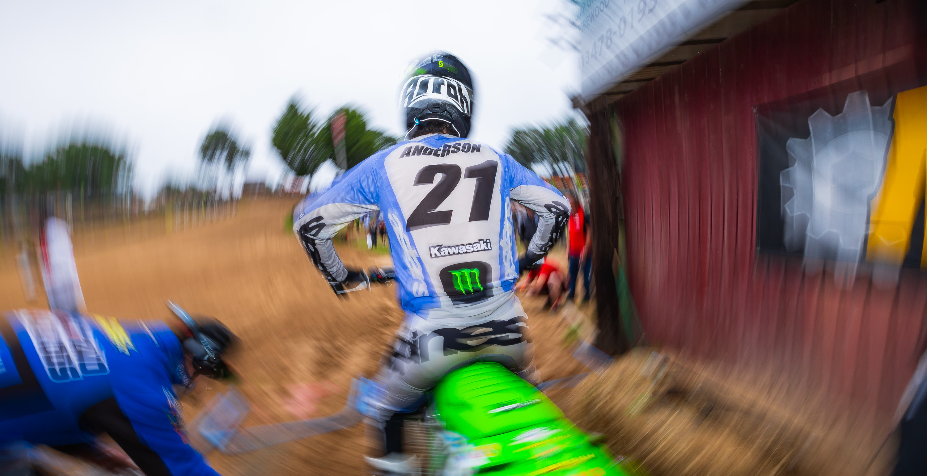 Jason Anderson wearing an Alpinestars mx gear set before a race near a red barn with blurred motion effect