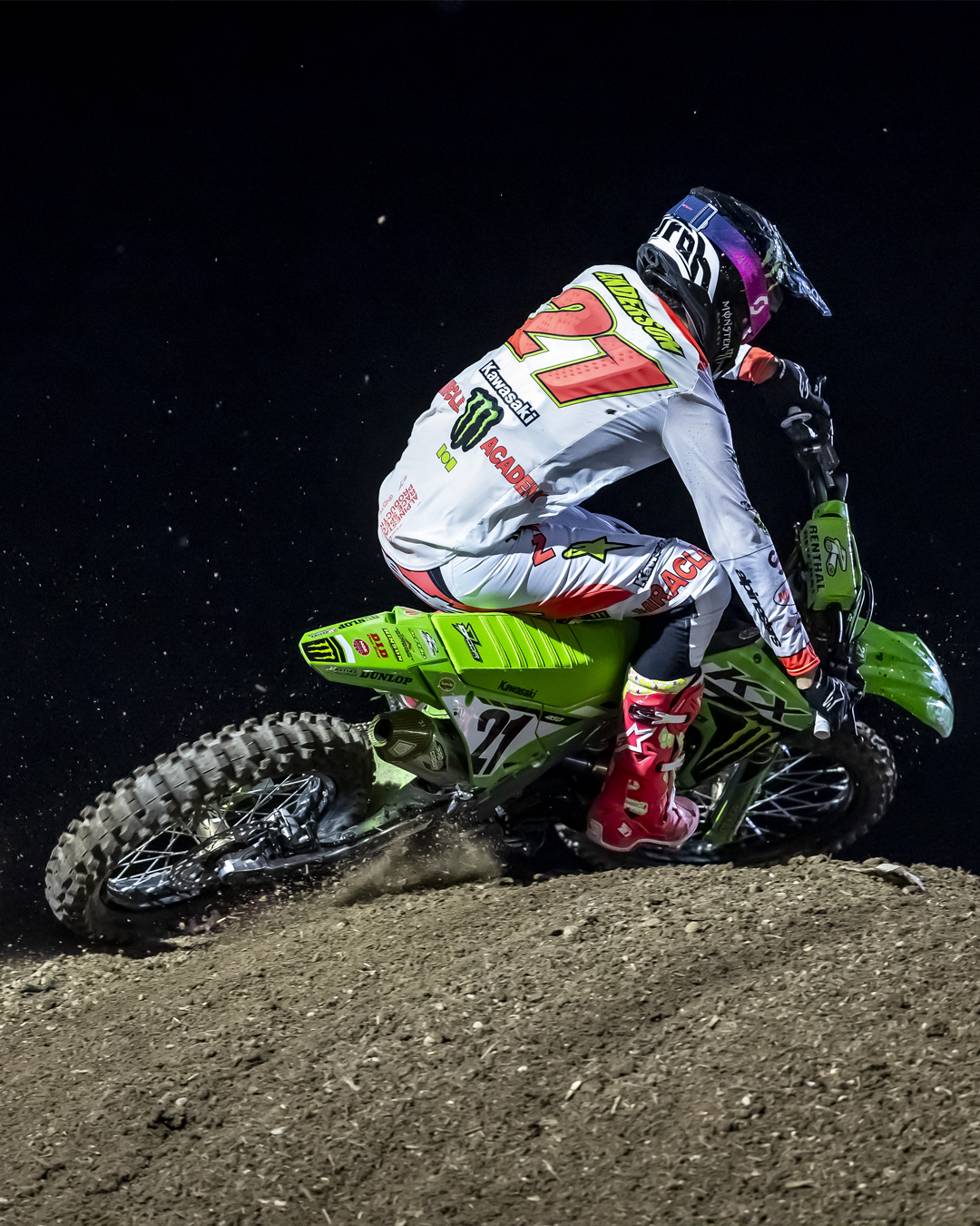 Motocross rider Jason Anderson in action on a dirt track at night.