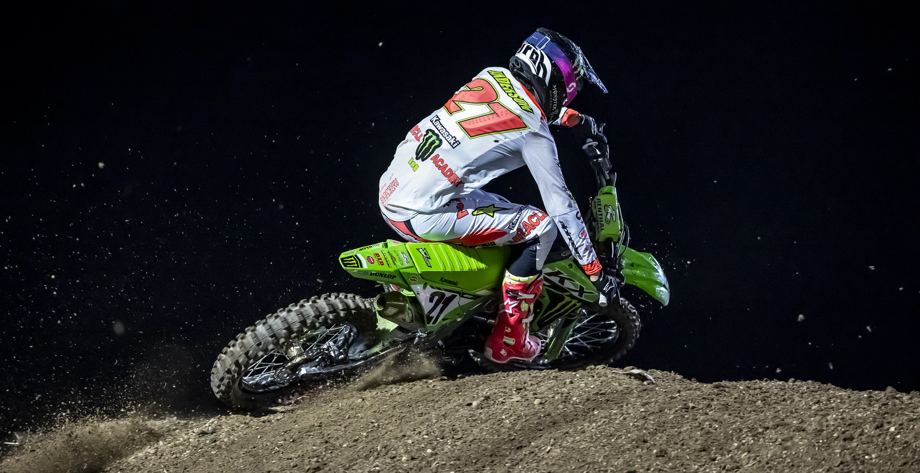 Motocross rider Jason Anderson in action on a dirt track at night.