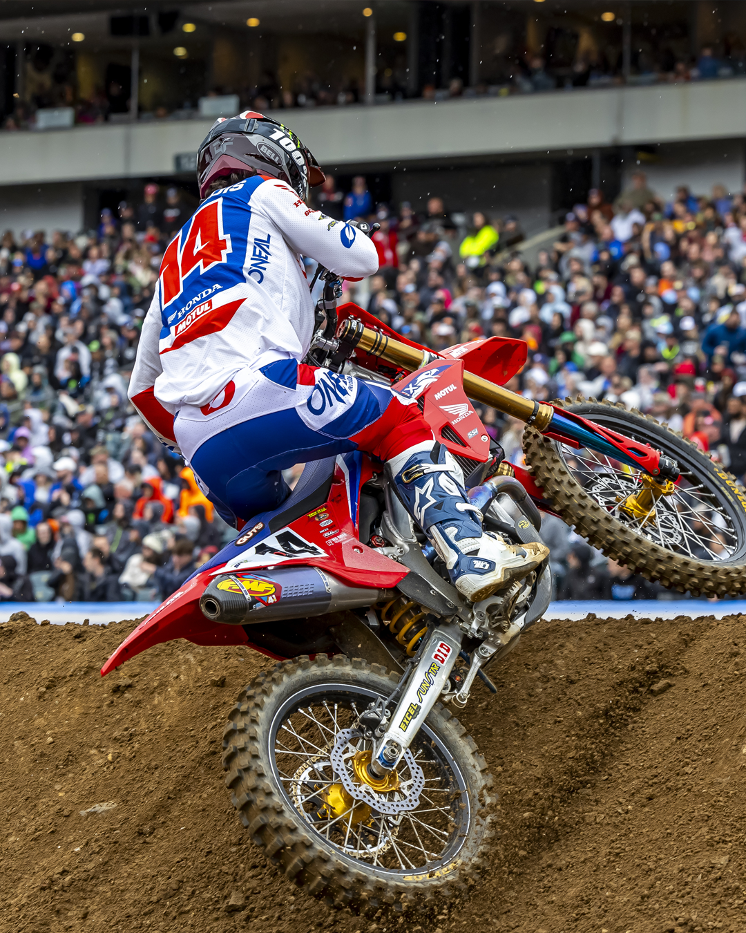 Motocross rider Dylan Ferrandis performing a jump on a dirt track with a crowd in the background, while wearing Alpinestars Tech 10 Boots