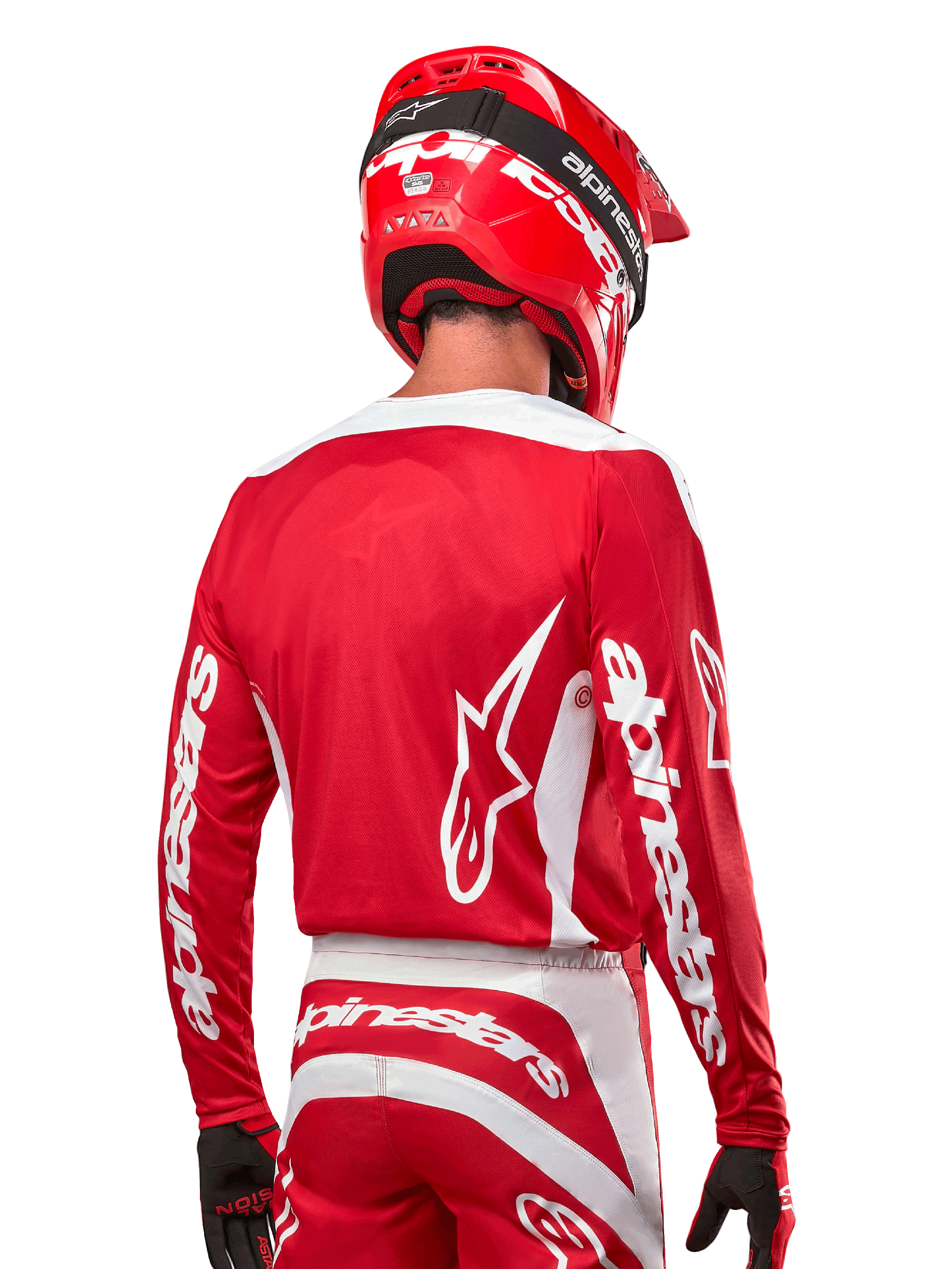 Motocross rider wearing Alpinestars 2024 Fluid Lurv Jersey, Mars Red and White, rear view showing white Alpinestars logo on back and branding on sleeves, paired with a matching red helmet and black gloves, professional off-road racing gear