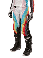 Alpinestars Women Stella 2024 Techstar Pants, Motocross Pants, Black Multicolor with diagonal red, yellow, and blue stripes, worn with black riding boots and white gloves, featuring protective black knee panels and bold branding for off-road racing.