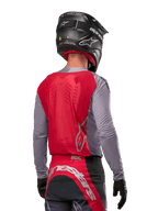 Motocross rider from behind wearing the Alpinestars 2024 Supertech Dade Jersey in Iron Red Berry and grey, featuring a breathable mesh back panel and silver logo accents, paired with a black helmet and matching racing pants for professional off-road performance