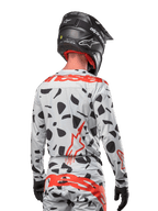 Motocross rider from the back wearing the Alpinestars 2024 Techstar Rantera Jersey in Haze Gray Camo, featuring a light gray base with black graphic spots and bold red Alpinestars logos on the back and shoulders, paired with matching pants and a black helmet.